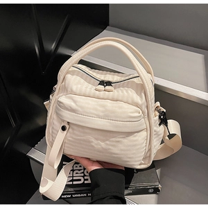 Detail of beige nylon crossbody bag with dual zippers and wide canvas shoulder strap