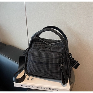 Close-up of dark grey grid pattern nylon bag featuring double metal zippers and textured fabric
