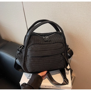 Macro detail of black checkered nylon crossbody bag with dual handles and zipper pocket