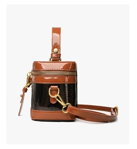Close-up of brown snake-embossed leather and glossy patent stitching on box handbag