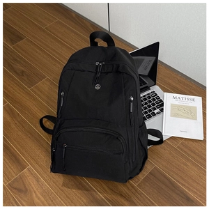 Detail view of large nylon backpack with multiple zipper pockets on wood floor