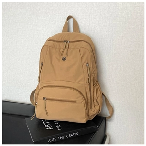 Macro shot of khaki nylon backpack on books featuring multiple pockets and durable zippers