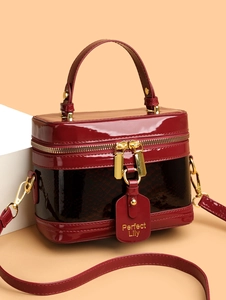 Detail of burgundy patent leather box bag with snake print and gold-tone zippers