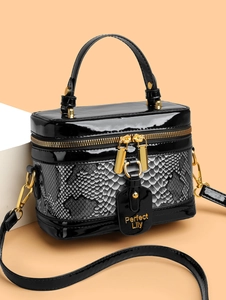 Macro detail of high-shine black patent leather trim and textured snake skin handbag