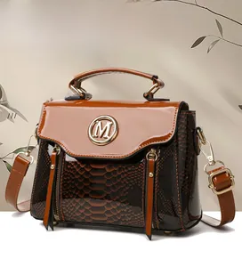Detail of snake skin texture and golden M logo on the brown leather crossbody bag