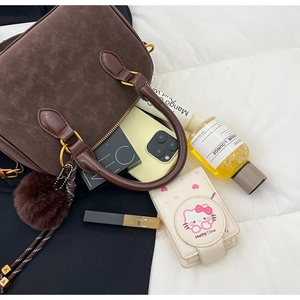 Détail du sac à main marron foncé mat avec pompon et poignée cylindrique lisse