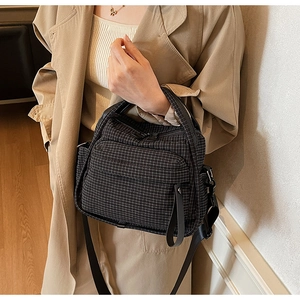 Detail of a casual black nylon crossbody bag with multi-zipper pockets and shoulder strap