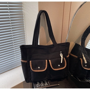 Detail of black corduroy tote bag featuring multi-pocket design and contrast brown piping