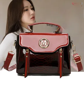 Detail of red snake pattern texture and gold metallic M logo on stylish crossbody handbag