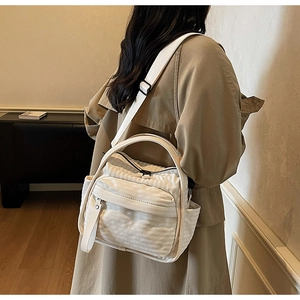 Modern white nylon crossbody bag with multiple pockets shown on model in trench coat