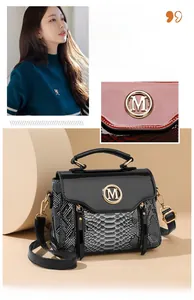 Detailed close-up of fashion crossbody bag with snake-embossed leather and golden M-logo