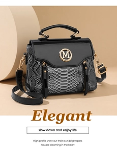 Detail of snake skin pattern stitching and golden M logo on fashionable crossbody bag