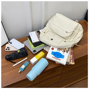 Detail view of large-capacity nylon backpack with multiple pockets on a wooden desk