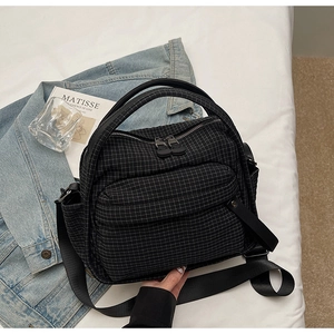 Detail of checkered nylon shoulder bag with double zippers and adjustable strap