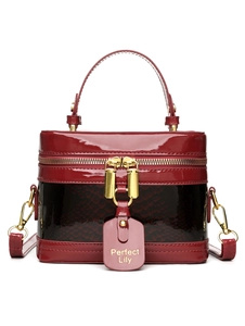 Detail of burgundy patent leather and snakeskin texture on handbag with gold zippers