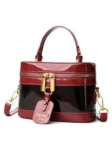 Detail of burgundy patent leather box bag with snakeskin texture and gold hardware