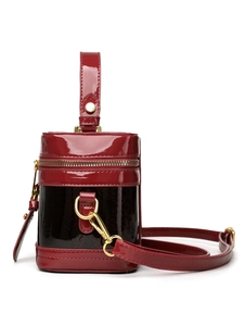 Detail of burgundy snakeskin textured leather and glossy patent handle on round handbag