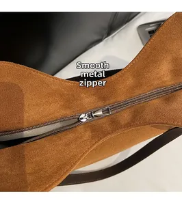 Détail du zip en métal argenté et texture suédée marron sur un sac fourre-tout