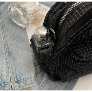 Close-up of black checkered nylon crossbody bag featuring side pocket and metal zipper