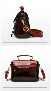 Detail view of red-brown gradient glossy snakeskin embossed handbag with gold metal hooks