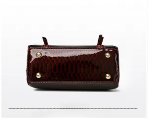 Detailed bottom view of stylish snakeskin pattern handbag with four gold protective studs