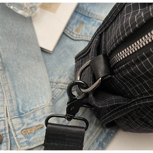 Close-up of black quilted nylon fabric with shiny metal hooks and buckle detail