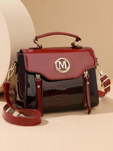 Detail of burgundy patent leather handbag with snakeskin texture and golden M logo