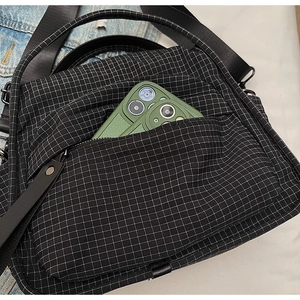 Detail of front zipper pocket on black and white checkered nylon crossbody bag with phone