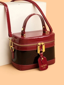 Detail of burgundy snakeskin texture and gold zipper on a retro box handbag