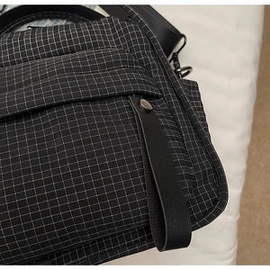 Detail of black grid nylon fabric on shoulder bag with metal buckle and strap