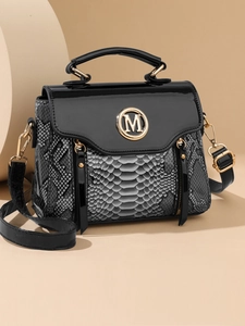 Detail of snake print texture and gold M logo on the black crossbody bag