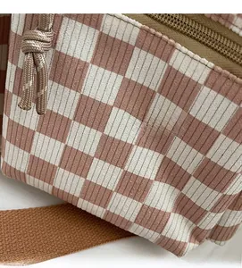 Detail of pink checkerboard corduroy fabric with sturdy brown strap and knot zipper
