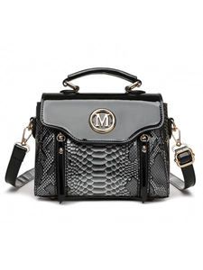 Detailed view of black snakeskin texture and golden M logo on stylish crossbody bag