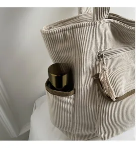 Detail of off-white corduroy tote bag showing side pocket and storage for water bottle