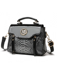 Close-up of gloss black leather and snake pattern with golden M logo on handbag
