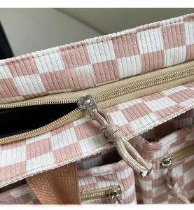 Close-up of a smooth metal zipper on a pink checkerboard corduroy tote bag detail
