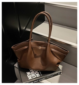 Détail du sac cabas en cuir litchi marron foncé montrant le grain fin et les ailes