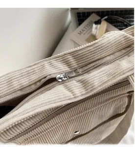 Detailed close-up of smooth silver metal zipper on a corduroy tote bag with fabric texture
