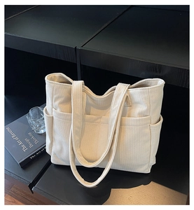 Detail of off-white corduroy tote bag with wide straps and functional side pockets