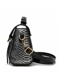 Detail of snake skin pattern texture and gold metal hardware on women shoulder bag