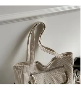Detail of corduroy handbag featuring cream texture, sturdy handle and front zipper pocket