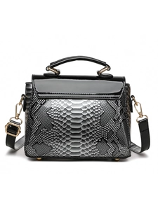 Detailed view of grey snakeskin embossed texture and black glossy patent leather handbag