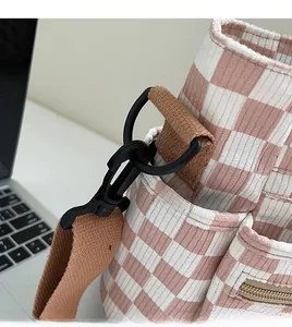 Detail of pink checkerboard tote bag with durable black hook and brown shoulder strap