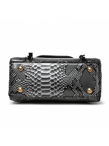 Macro detail of snake skin leather texture with gold metal studs on handbag base