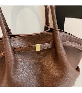 Détail du sac cabas en cuir grainé marron avec accessoires métalliques dorés élégants