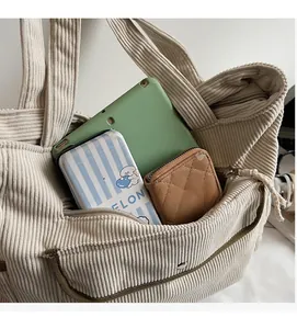 Detail of spacious corduroy tote bag showing interior storage for tablets and journals