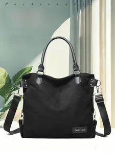 Detail view of large black suede tote bag with leather handles and long shoulder strap
