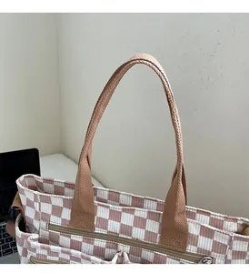Detail of pink checkerboard tote bag with durable brown handles and zip closure