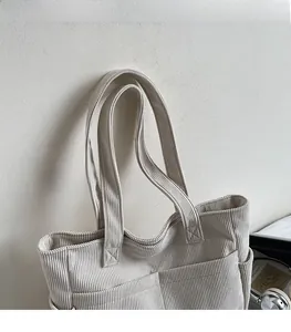Detail of wide shoulder strap and textured corduroy fabric on a cream tote bag