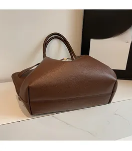 Détail du cabas en cuir grainé marron foncé avec une boucle en métal doré chic